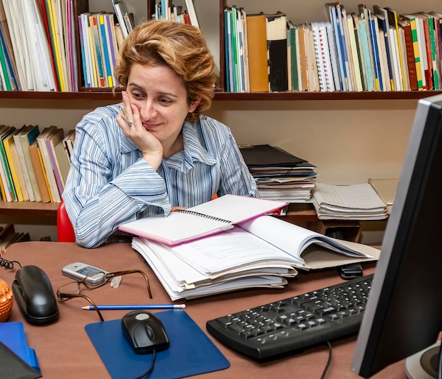 A student studying diligently at a desk covered in textbooks and notes, with a computer displaying their GPA and credit completion rate. The room is well-lit and organized, symbolizing good study habits.