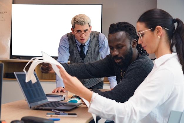 A diverse group of professionals actively participating in a hands-on workshop, with laptops and training materials spread across the table. The atmosphere is collaborative and engaging, with attendees focused on the instructor's demonstration.