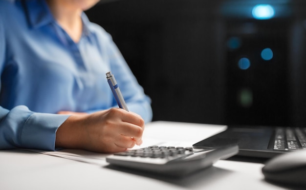 A person sitting at a desk, reviewing financial documents and using a calculator, with a calendar in the background marked with 